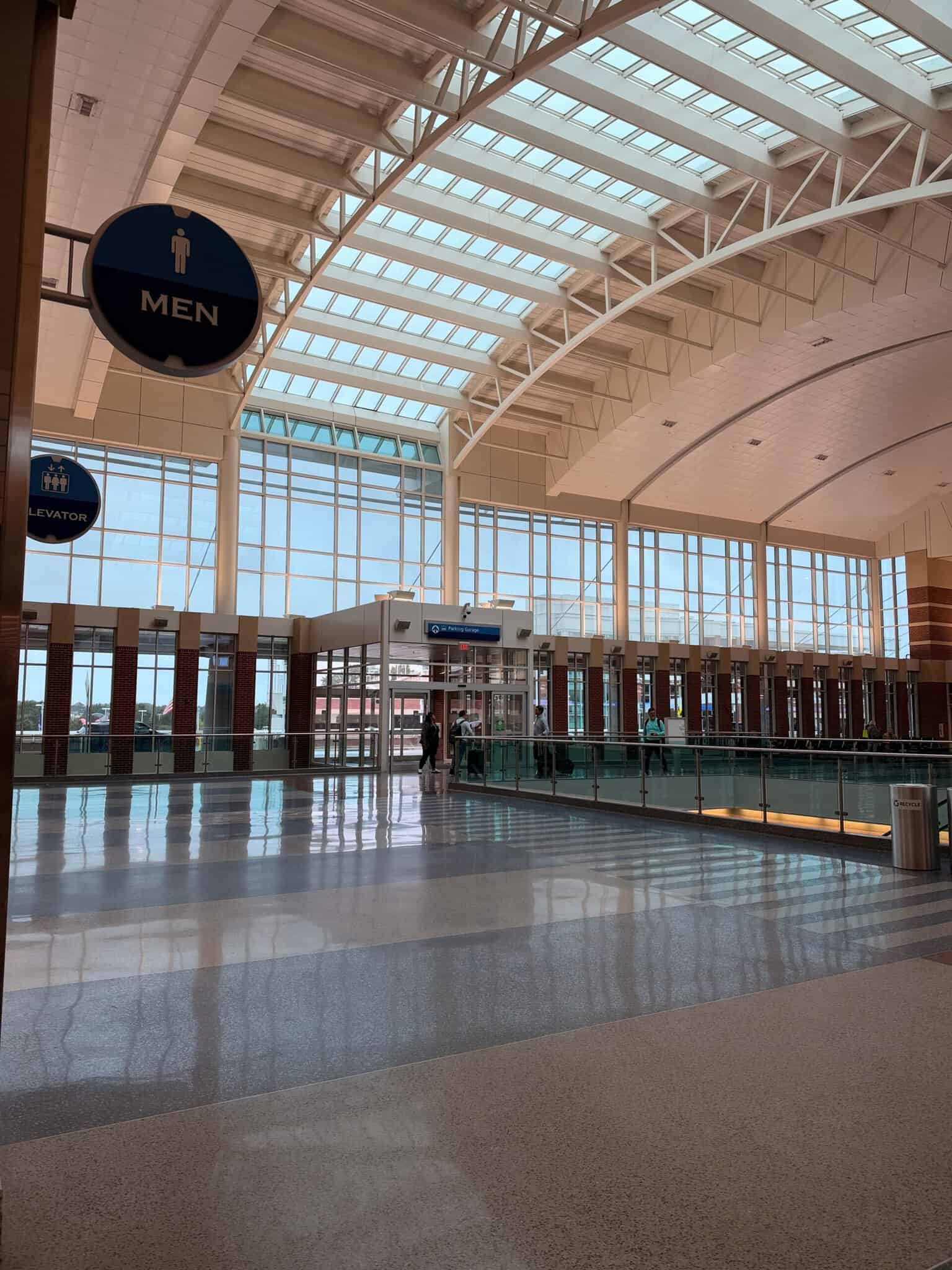 Main hall at Richmond International Airport (RIC) with white steel arches, a long skylight roof and floor-to-ceiling windows reflecting on the terrazzo floor