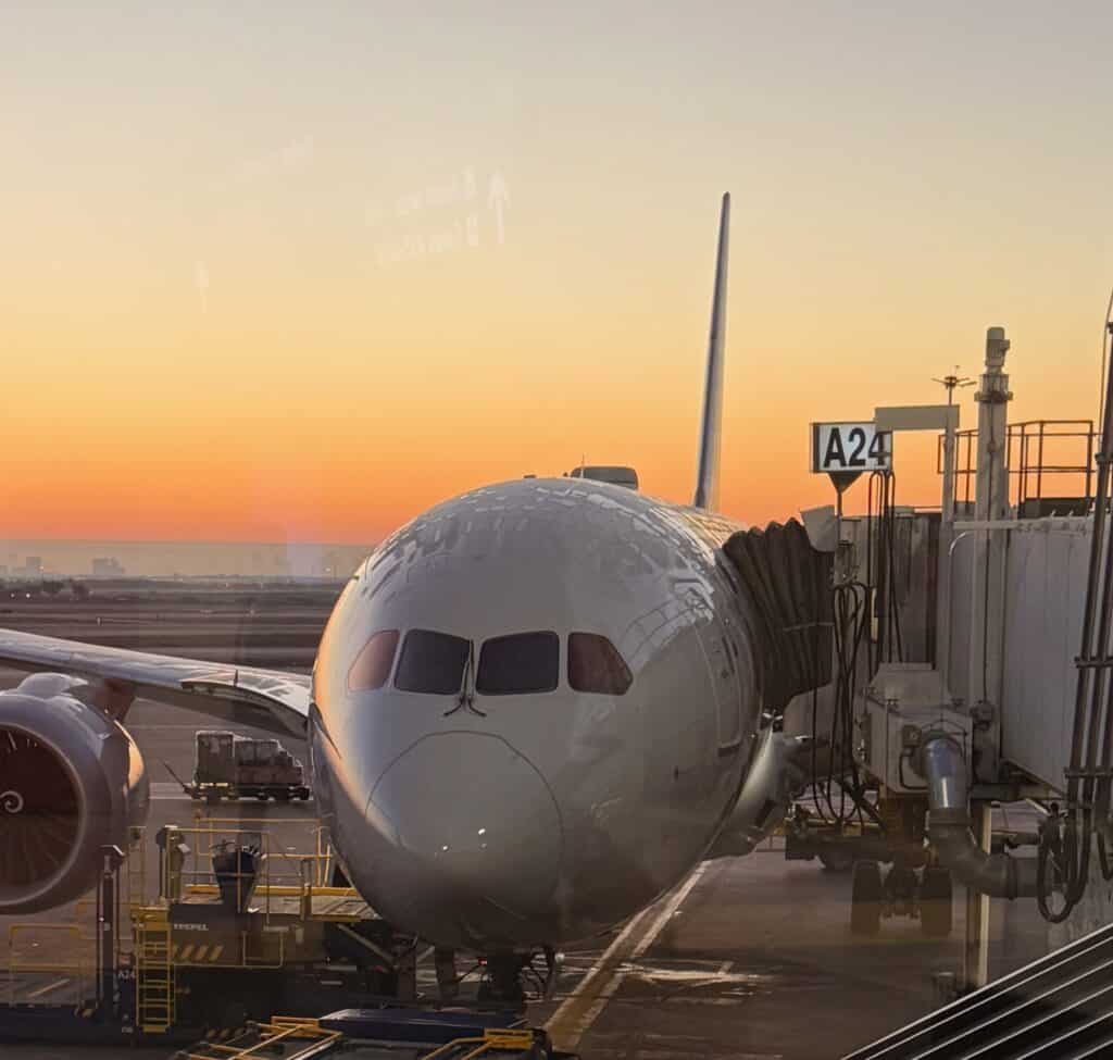 A jet parked at Gate A24 at DFW Terminal A with an orange sunrise glowing over the tarmac - aviation photography by Anthony Yandow