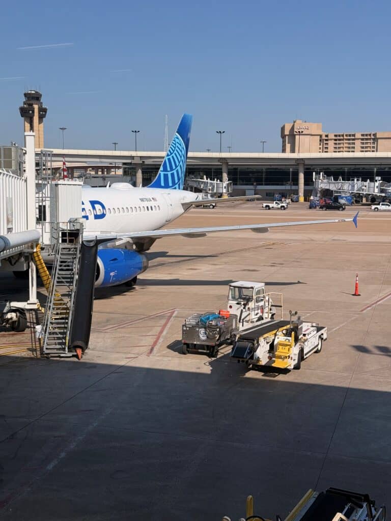 A United jet parked at the gate on the DFW tarmac with the airport control tower and the in-airport Hyatt hotel visible in the background - aviation photography by Anthony Yandow