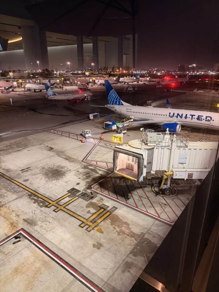 United jets parked at Terminal 7 Gate 70A at LAX at night, showing the low, boxy terminal building against the city skyline - aviation photography by Anthony Yandow