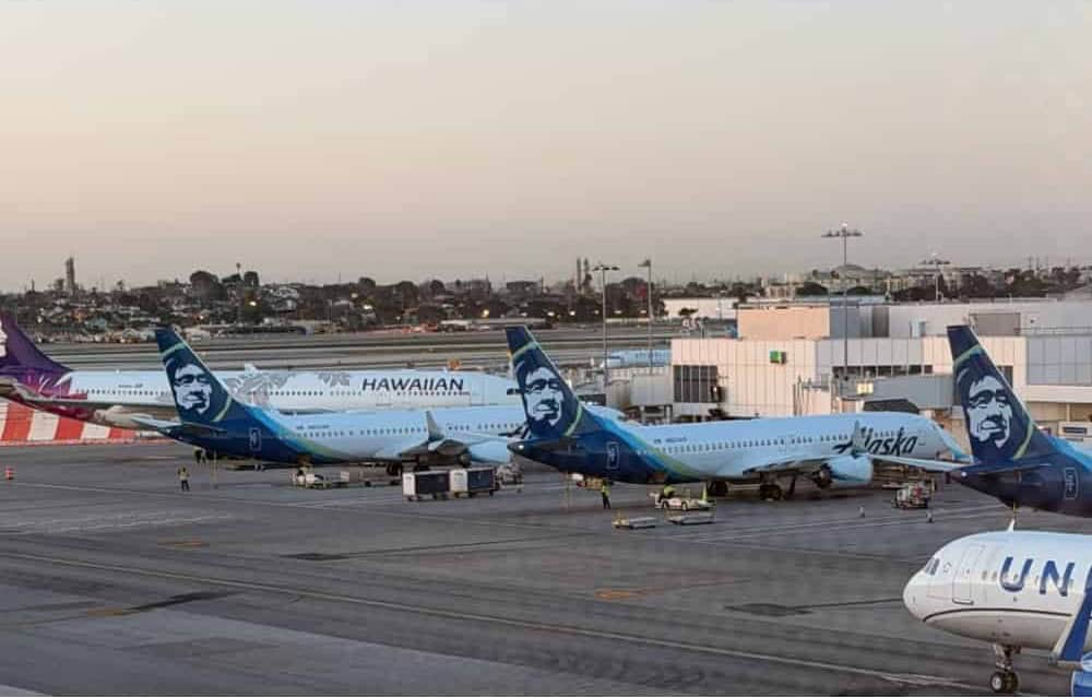 Alaska, Hawaiian and United jets lined up at the gates at dusk