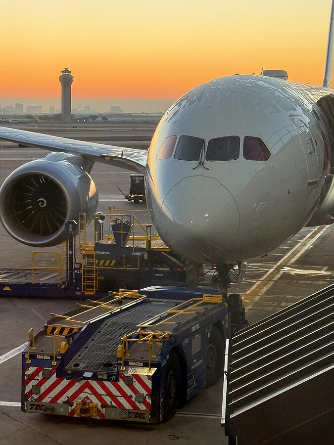 787 Ready for Pushback at DFW Sunrise A Boeing 787 at the gate at DFW at sunrise with the pushback tug connected and the control tower behind it