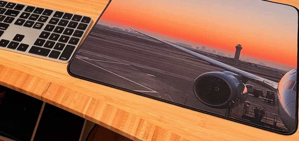 Mouse pad printed with a Boeing 787 at sunrise next to a keyboard